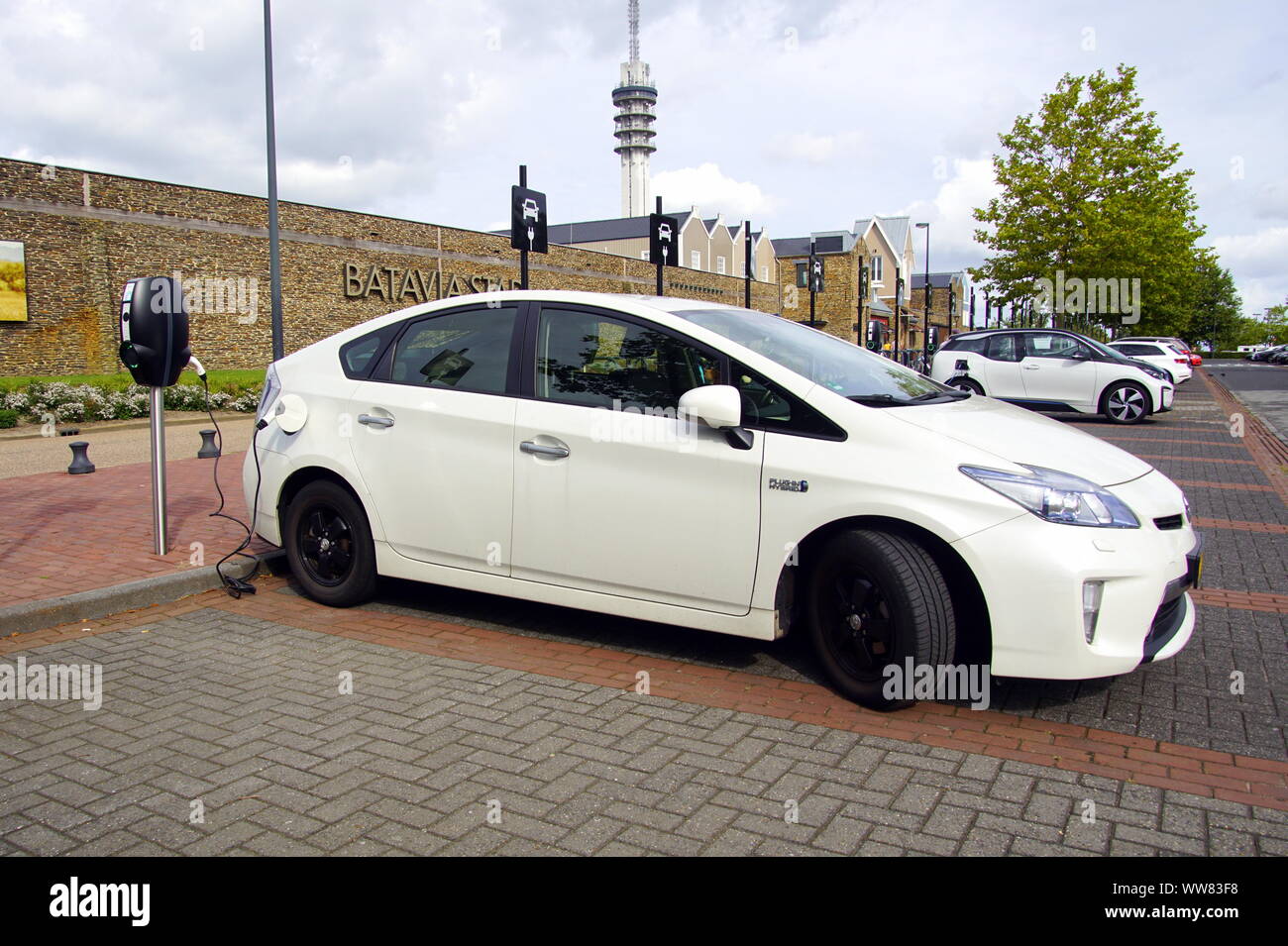 Lelystad, Paesi Bassi - 1 Settembre 2019: Bianco Toyota Prius essendo caricato su di un parcheggio pubblico. Nessuno nel veicolo. Foto Stock