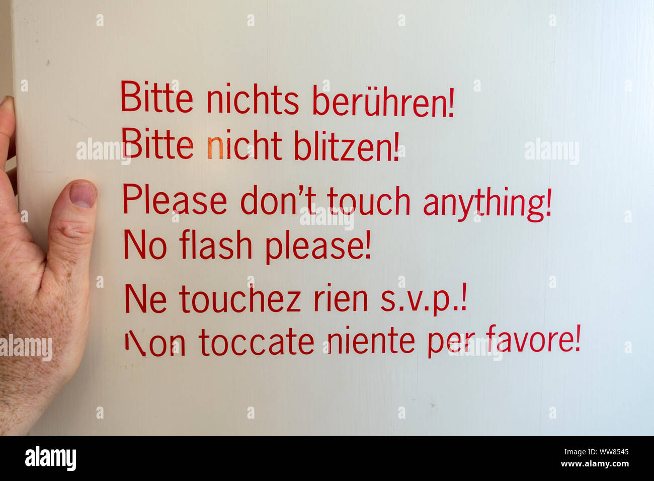 Mano che tiene un "Si prega di non non toccare nulla' & 'No Flash' segno dentro il palazzo di Nymphenburg (Schloss Nymphenburg), Monaco di Baviera, Germania. Foto Stock