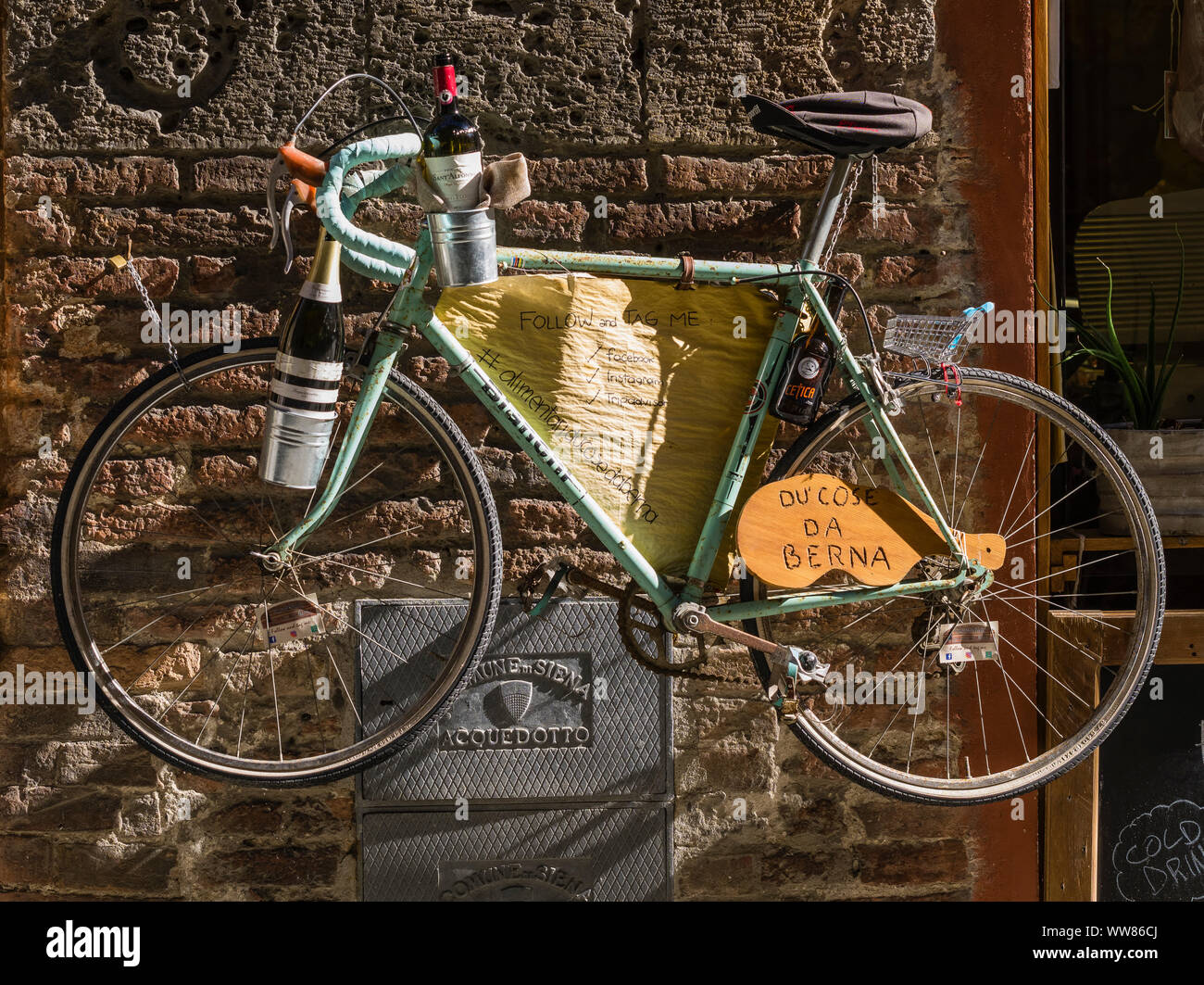 La bicicletta come una decorazione della facciata di un negozio di vino nel centro storico di Siena Foto Stock