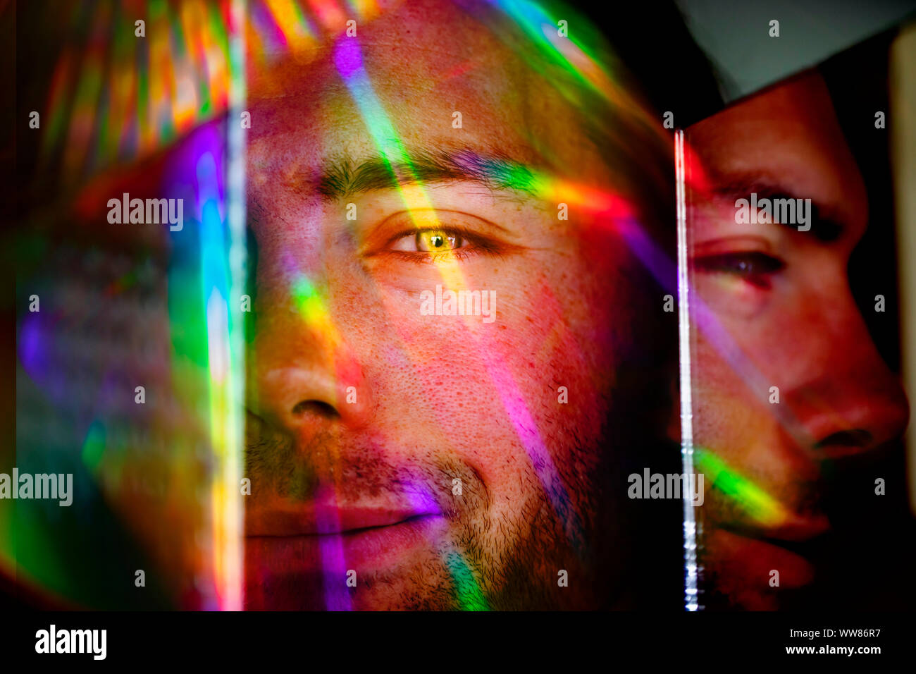 Giovane uomo in luce colorata e uno specchio Foto Stock