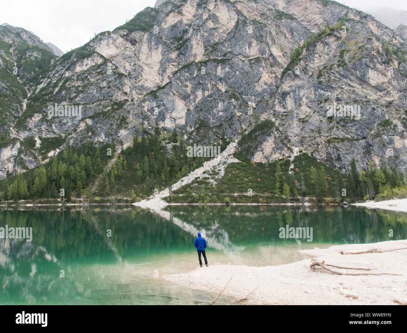 Escursione autunnale intorno al Lago di Braies nelle Dolomiti, Italia, uomo in piedi sulla riva e guardando sopra il lago Foto Stock