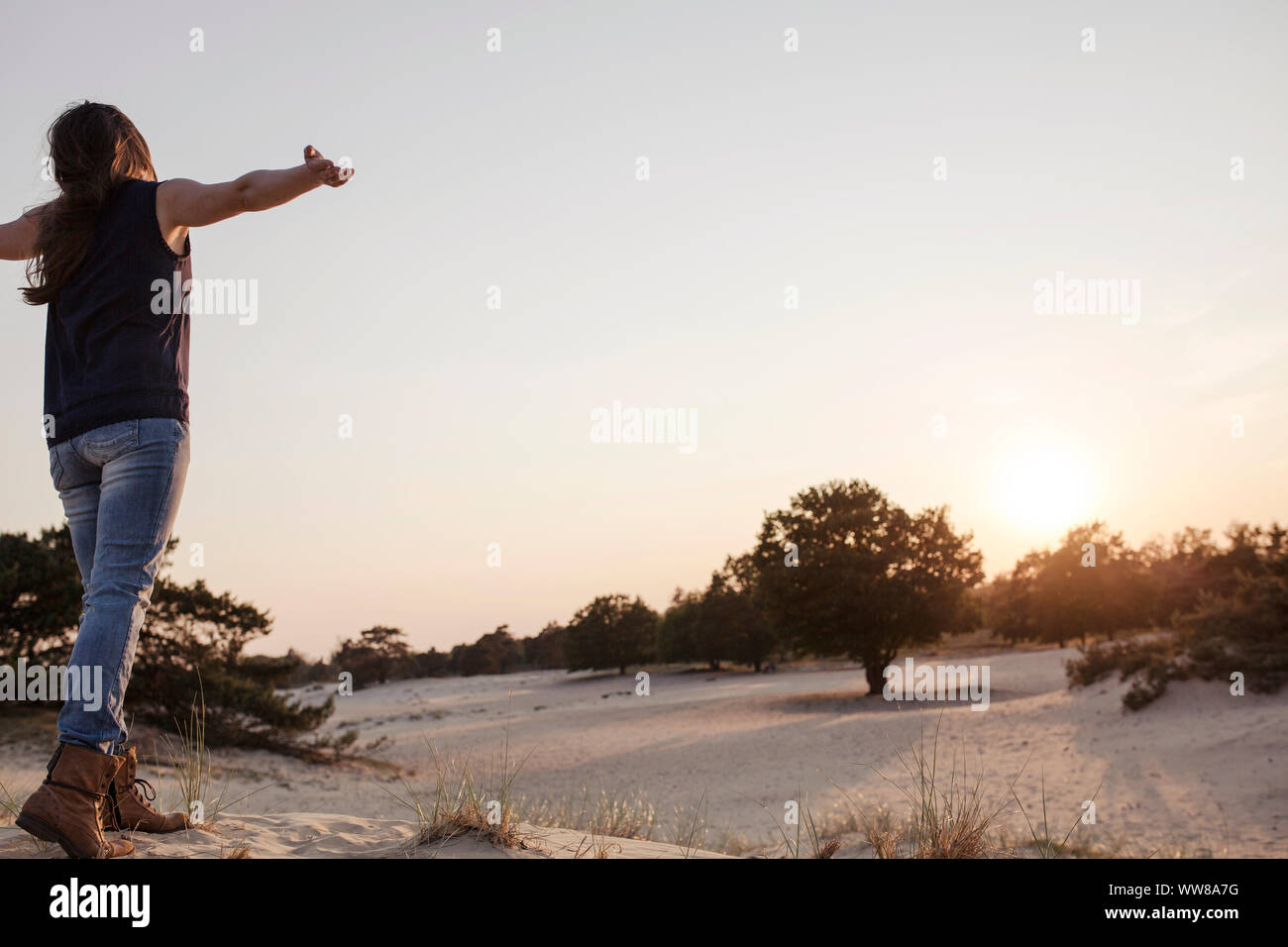 Giovane donna in un paesaggio di dune, braccia distesa, sensazione di libertà Foto Stock