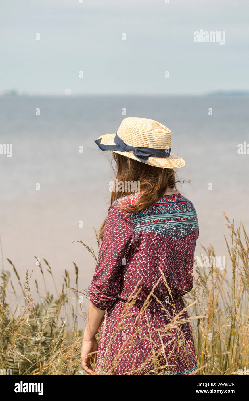 Giovane donna in abiti estivi e cappello di paglia al litorale Foto Stock