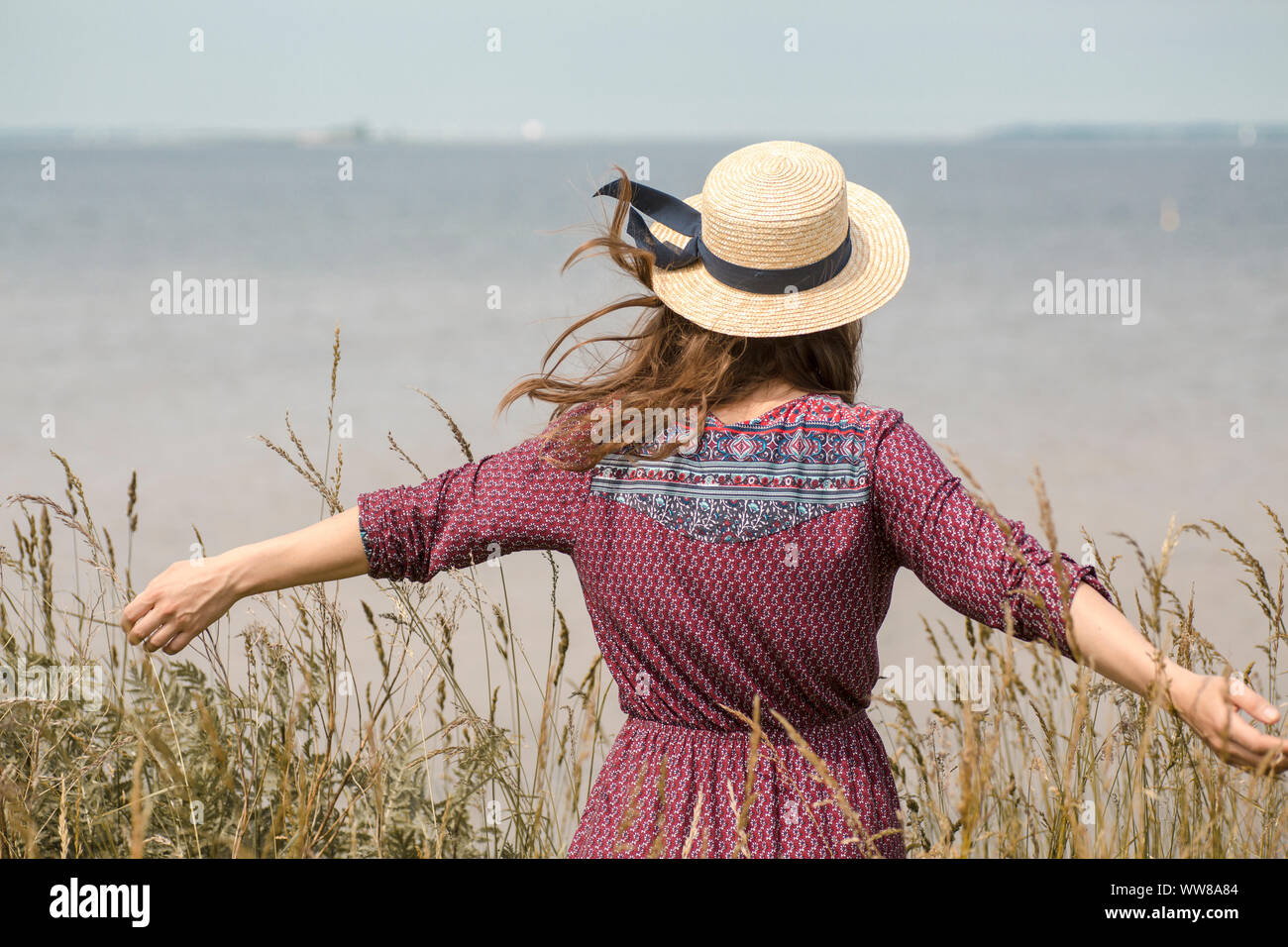 Giovane donna in abiti estivi e cappello di paglia al litorale Foto Stock