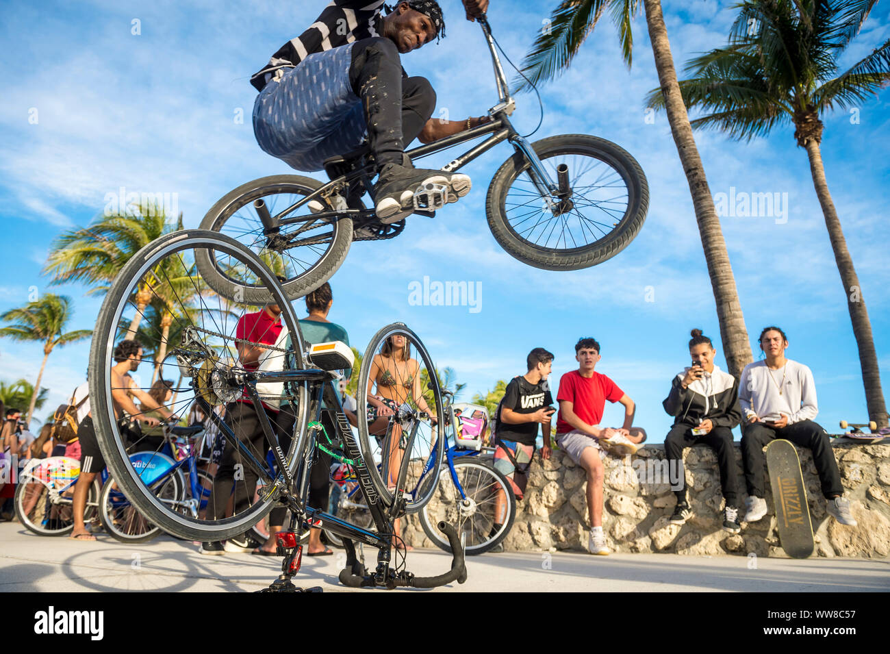MIAMI - Dicembre 27, 2017: un giovane temerario ciclista esegue uno stunt saltare sopra un altro noleggio di fronte agli spettatori sulla passeggiata sul lungomare. Foto Stock