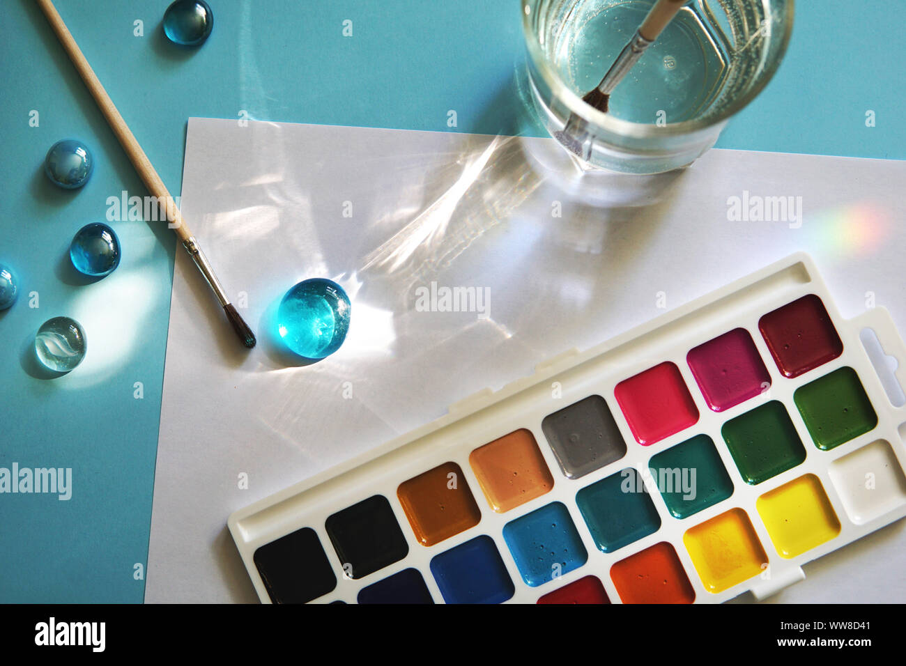 Luogo di lavoro di un acquerello artista-pittore. Sfondo blu, nuova bellissima vernici e brashes. Il concetto di scuola. Foto Stock