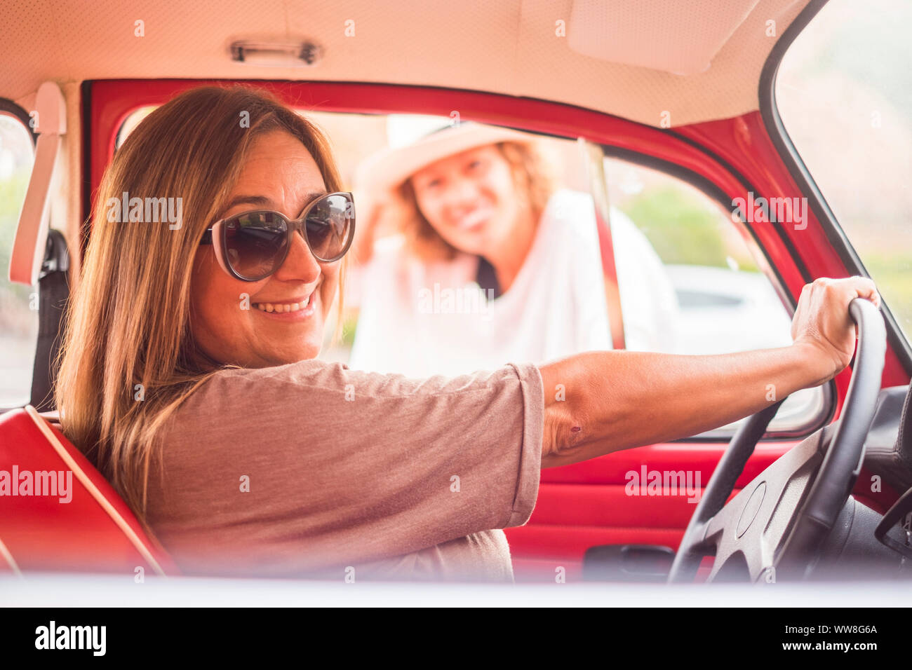 Vintage e retrò concetto con due femmine in amicizia insieme con un rosso leggendario auto, di libertà e di uno stile di vita alternativo concetto Foto Stock