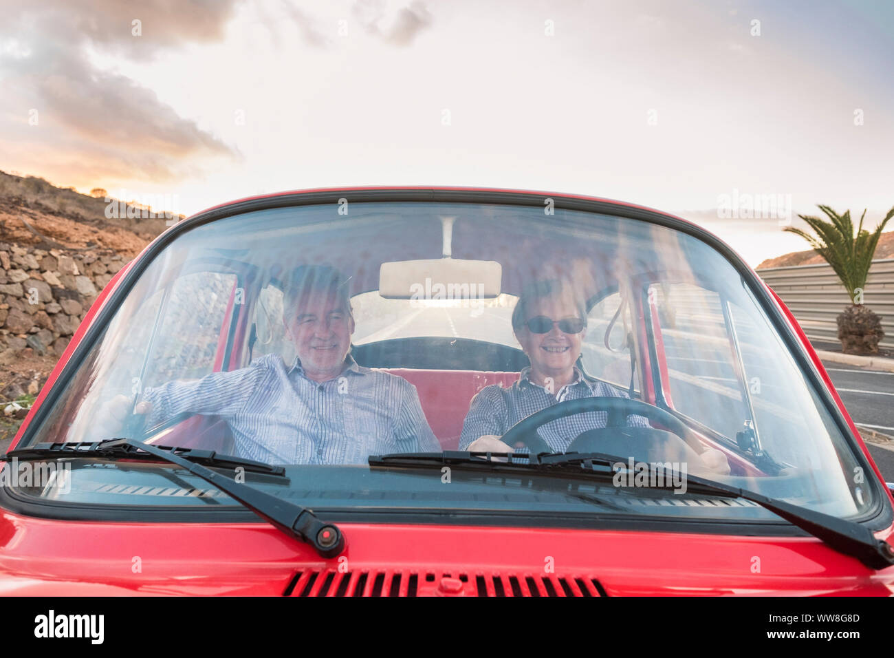 Nizza adulto giovane unità e amore all'interno di un vecchio rosso vintage auto parcheggiate sulla strada, sorrisi e divertirsi viaggiando insieme, di felicità e di stile di vita per la gente simpatica, estate tempo di vacanza e di viaggio Foto Stock