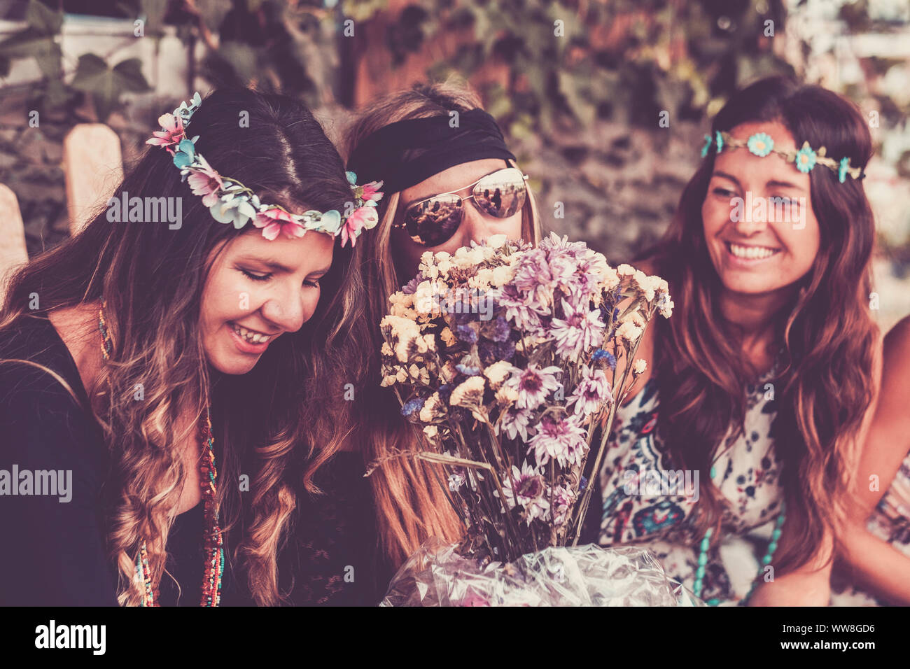 Giovani donne e ragazze in amicizia tutti insieme per celebrare e divertirsi in un bio luogo naturale, sorrisi e ridere per gruppo di hippies persone concetto alternativo stile di vita Foto Stock