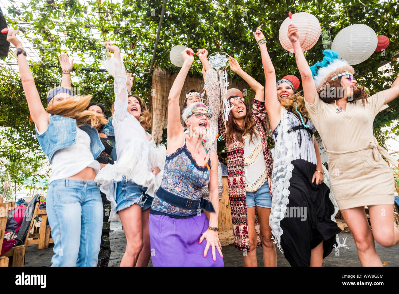 Gruppo di crazy donne di età mista da giovani a vecchi divertirsi e ballare tutti insieme in un stile hippy evento, celebrando gruppo concetto di persone con vestiti colorati e la felicità Foto Stock
