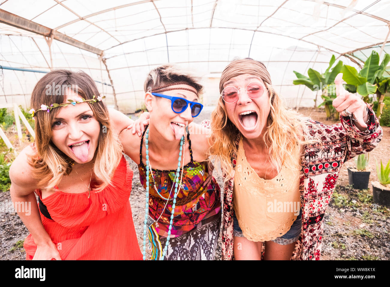 Un gruppo di persone giovani caucasici modello abbracciando le donne e reso pazzo espressione con facce mentre hanno divertimento. follia e il concetto di godimento per attraente signore in hippy vestiti colorati. evento di celebrazione. Foto Stock