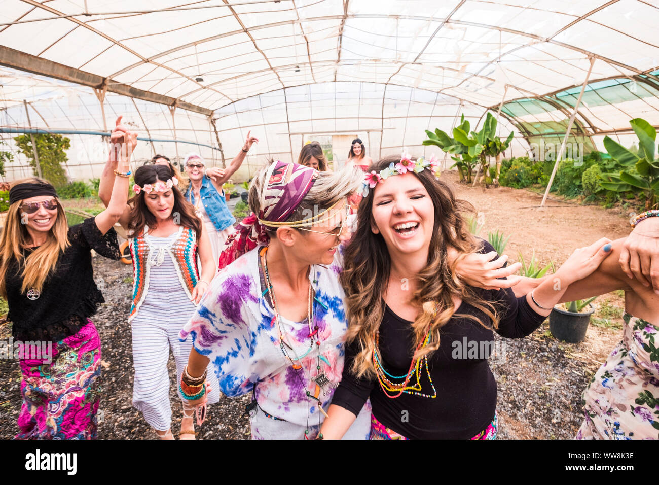 Giovani donne e ragazze in amicizia tutti insieme per celebrare e divertirsi in un bio luogo naturale. sorrisi e ridere per gruppo di hippies persone concetto alternativo stile di vita Foto Stock