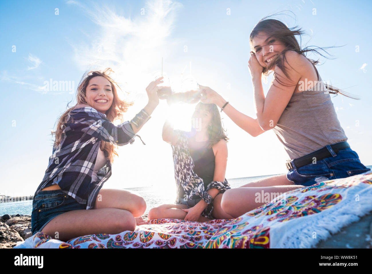 Un gruppo di giovani donne amico di bere insieme un succo di frutta su una spiaggia di roccia in Tenerife. Rapporto per una squadra di godere la vacanza e felicità. outdoor persone attive Foto Stock