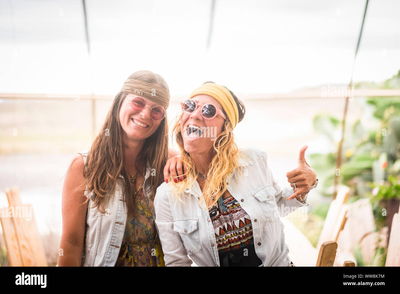 Paio di crazy femmine amici divertirsi e godere di uno stile di vita hippy che indossa il vecchio stile retrò abbigliamento e accessori moda e amicizia per le giovani donne del Caucaso Foto Stock