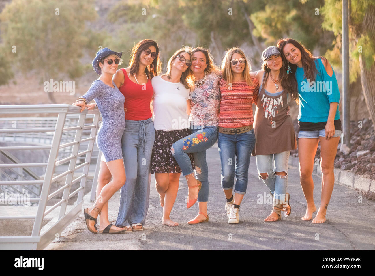 Il gruppo di sette bello e belle ragazze caucasici giovani donne di divertirsi e ridere e sorrisi per esterno in prossimità dell'oceano durante il tramonto. retroilluminazione paople godendo il tempo libero attività insieme Foto Stock
