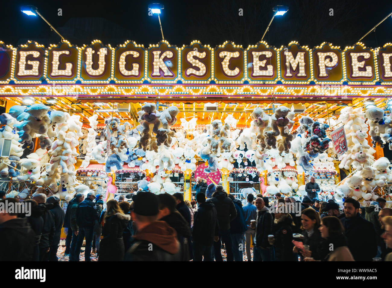 Decine di giocattolo animali appendere al di sopra di una lotteria-come il gioco mentre i partecipanti alla fiera a piedi passato una notte a una fiera di Amburgo, Germania Foto Stock