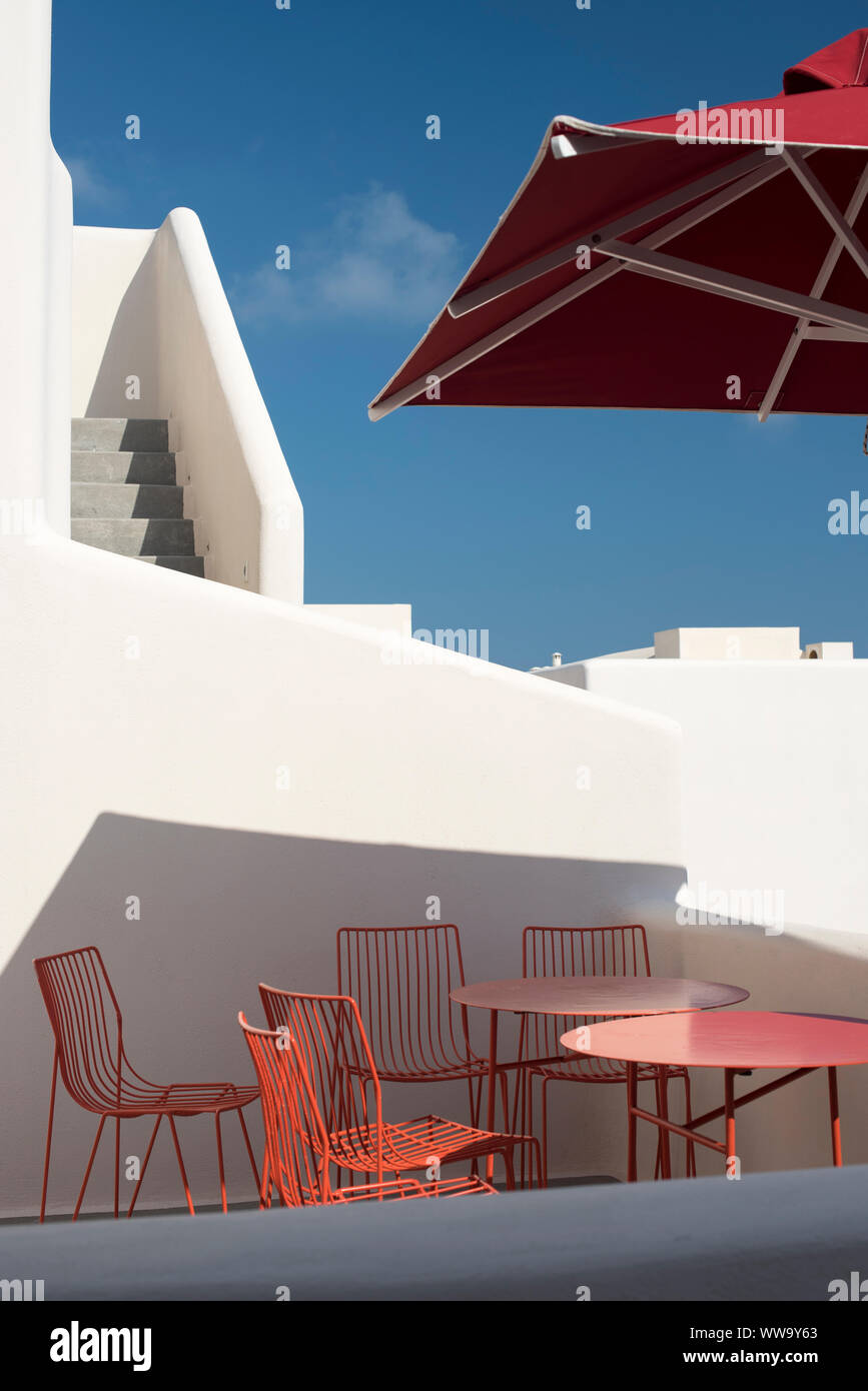 Santorini, Grecia - 23 Giugno 2018: Rosso tavoli e sedie sotto un ombrello rosso nel quartiere Pygros in Santorini in estate. Foto Stock