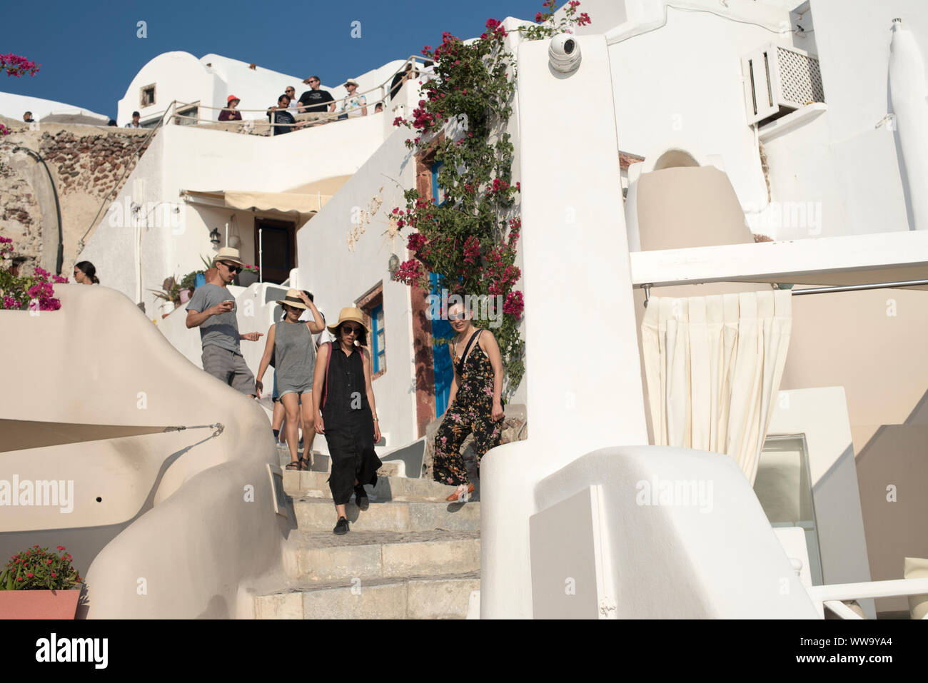 Santorini, Grecia - 24 Giugno 2018: Turisti in cappelli di paglia e occhiali da sole un giro giù le scale di pietra di Oia, una popolare destinazione turistica sul norther Foto Stock