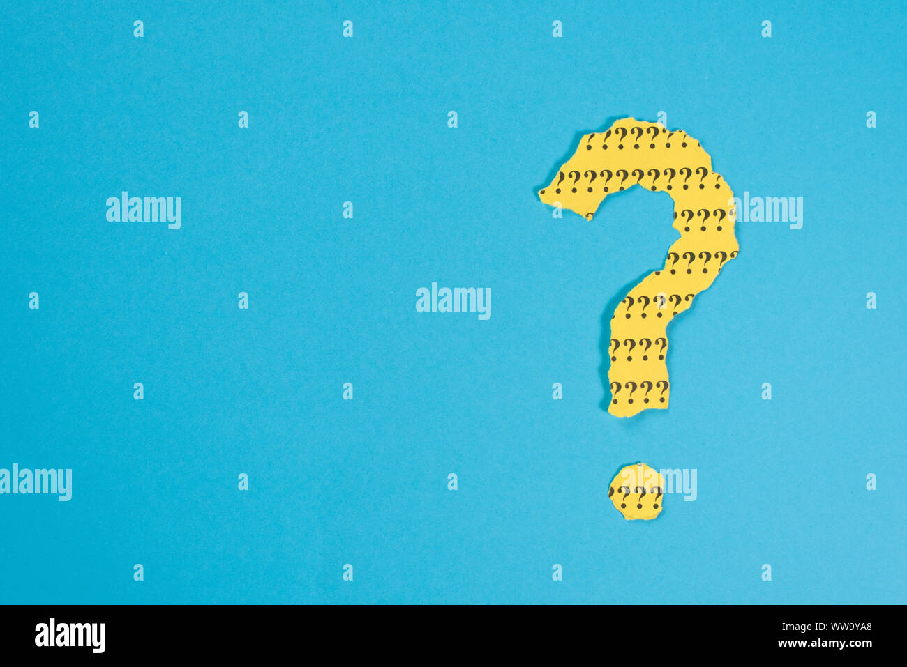 Punto interrogativo da un lacerate carta gialla su sfondo blu con una copia dello spazio. Concetto di FAQ, Q e un, domande e riddle Foto Stock