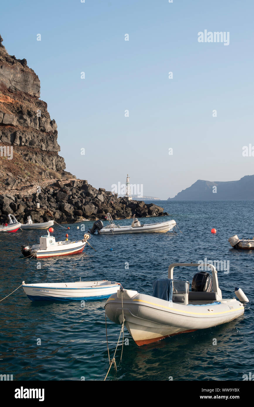 Santorini, Grecia - 24 Giugno 2018: barche da pesca ormeggiate sotto le scogliere rocciose nella baia di Ammoudi in Oia - Santorini. Foto Stock
