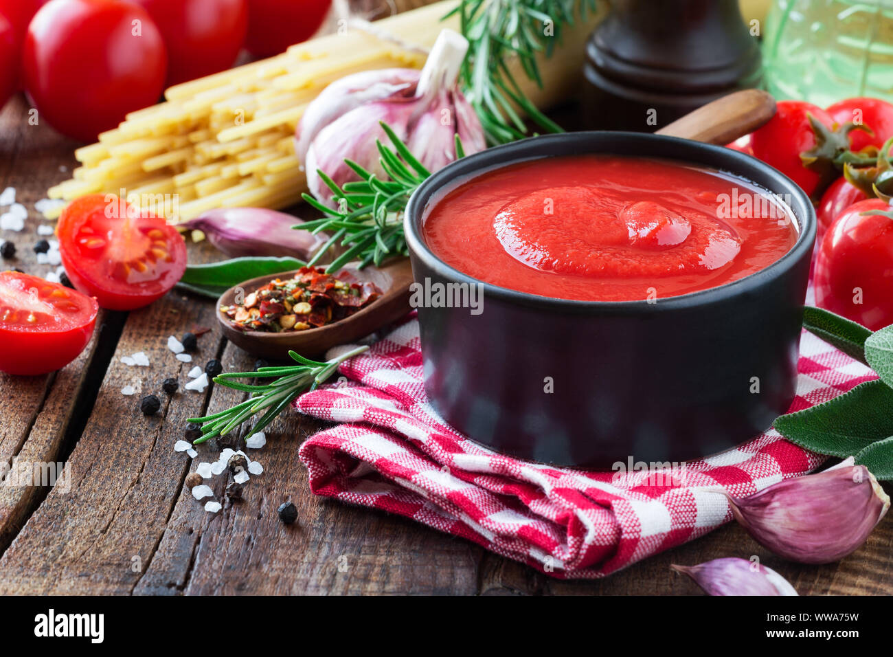 Salsa di pomodoro o ketchup in una ciotola nera con cottura Ingredienti in background Foto Stock