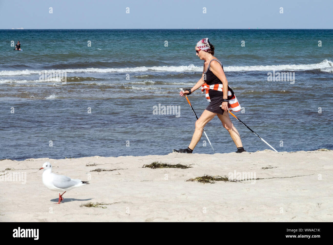 Donna anziana Nordic Walking lungo la spiaggia Mar Baltico Germania stile di vita sano anziano Beach walking donna anziana attiva passeggiata veloce Foto Stock