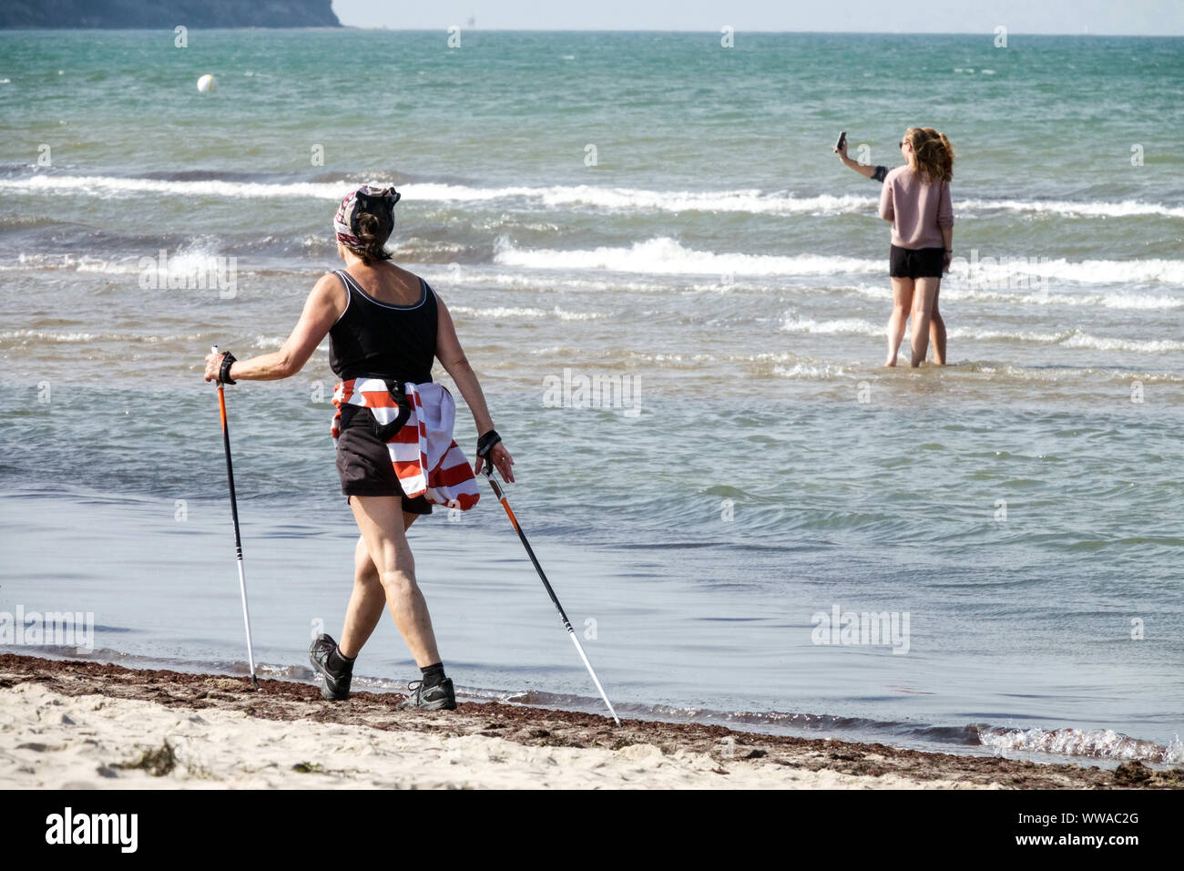 Donna anziana nordic Walking lungo la spiaggia Mar Baltico Germania invecchiamento attivo Foto Stock
