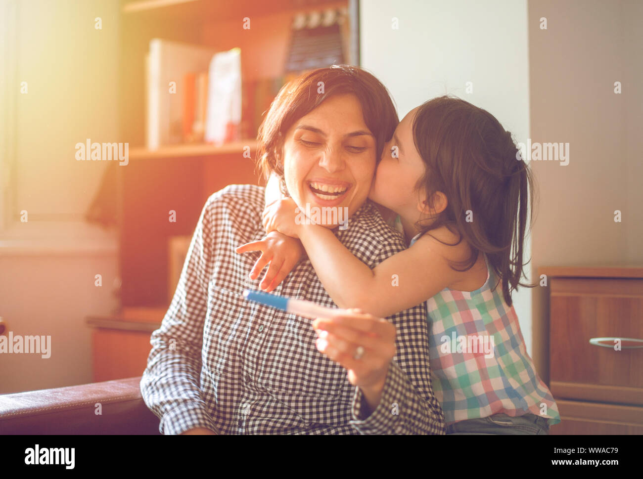 Madre godendo con sua figlia mentre guardando il positivo al test di gravidanza Foto Stock