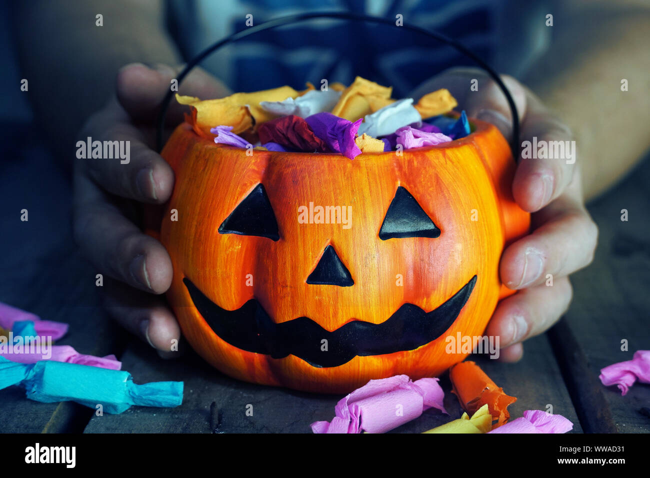 Tenere in mano la richiesta di zucca per candy su sfondo scuro. Foto Stock