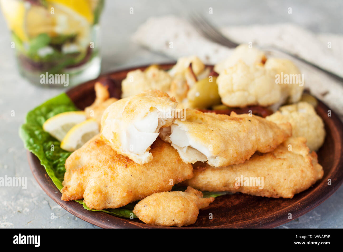 Pastellati bastoncini di pesce serviti con cavolfiore e erbe aromatiche fresche Foto Stock