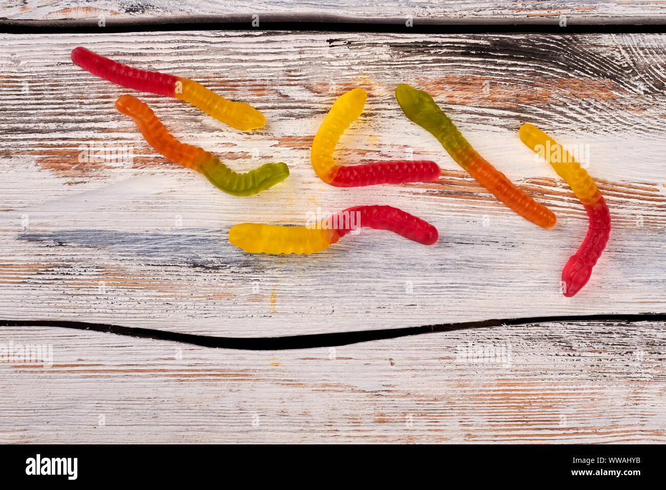 Vermi gummie colorate su sfondo di legno. Foto Stock