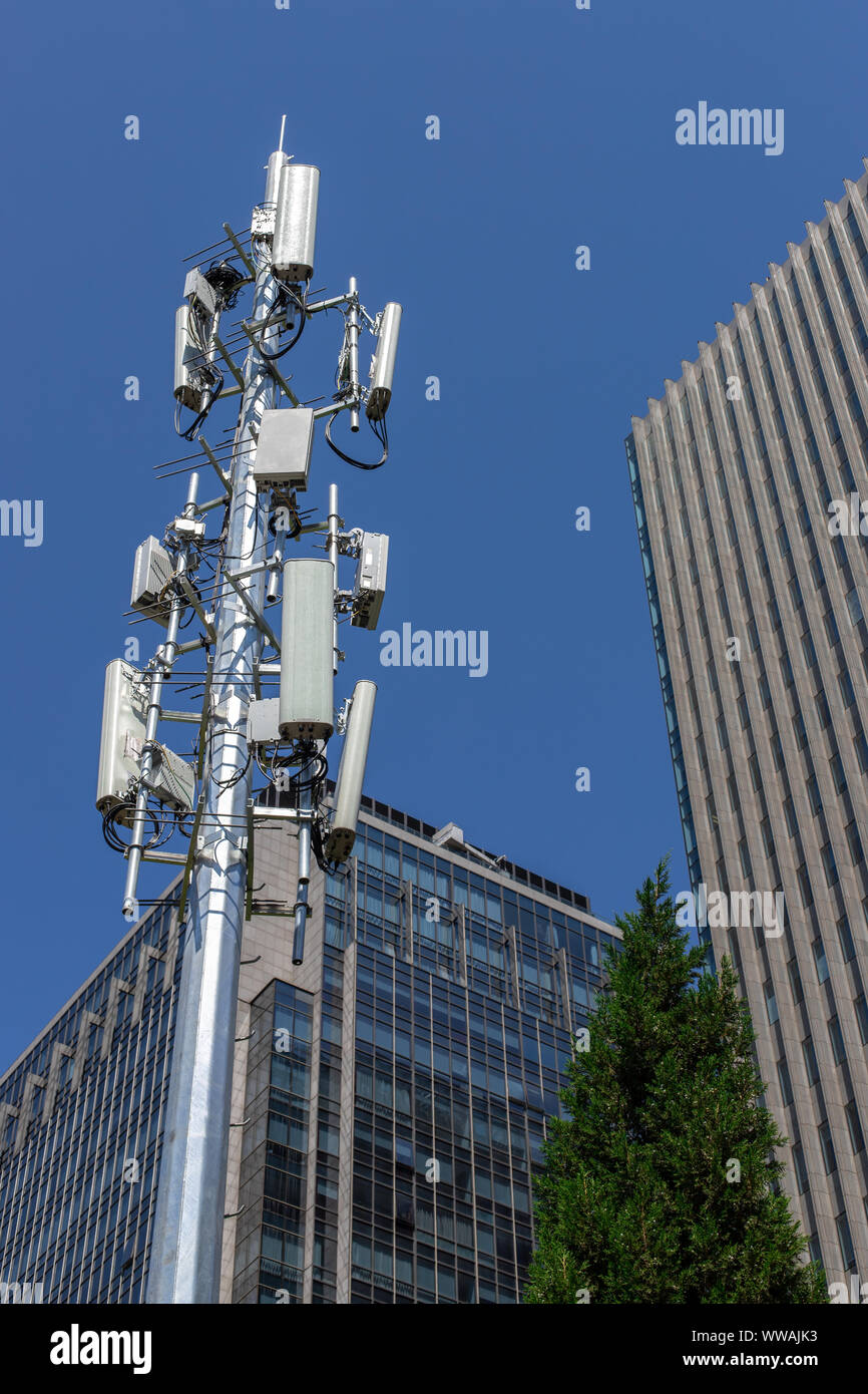 Quinta generazione torre cellulare. Le comunicazioni cellulari contro lo sfondo di un edificio per uffici e cielo blu. GSM 5G. Foto Stock