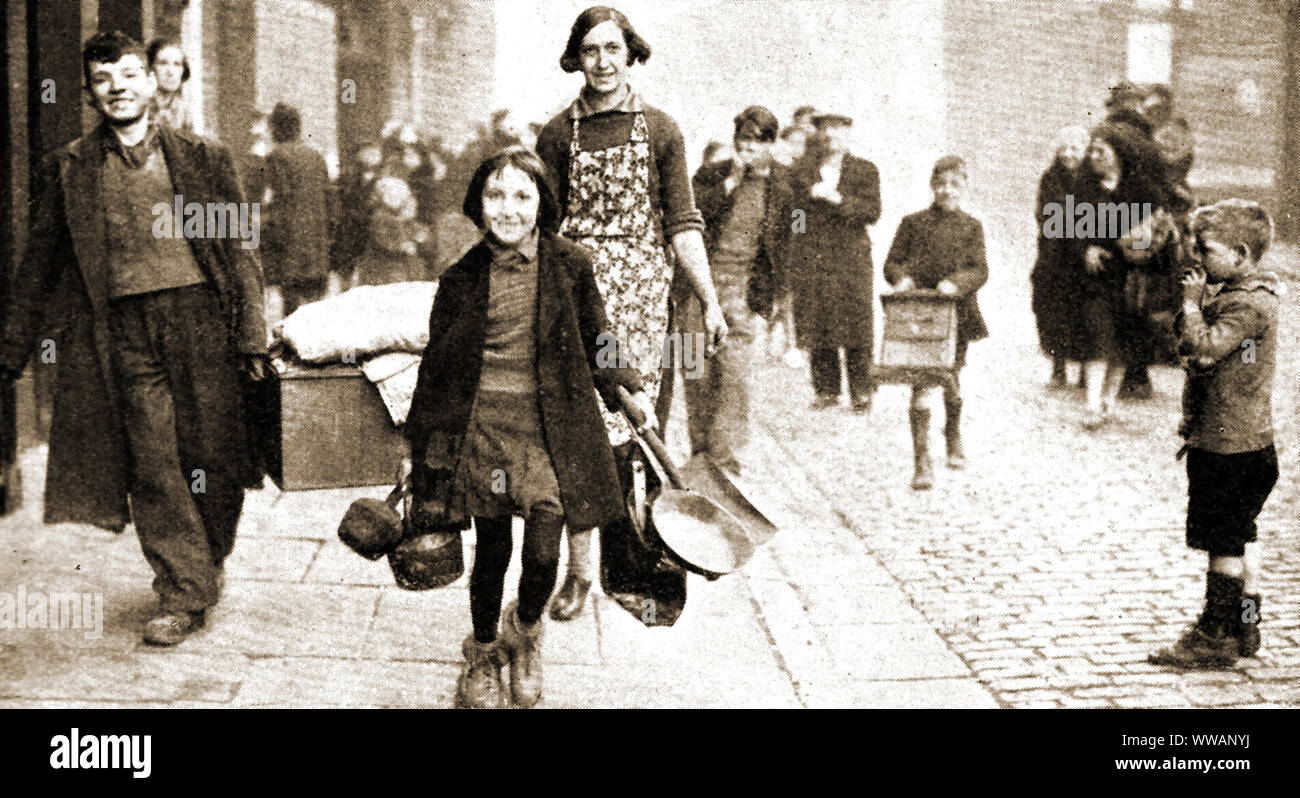 Durante la Seconda guerra mondiale - una sorprendentemente allegro senza dimora della famiglia di Liverpool che trasportano i loro averi dopo una notte di raid dai tedeschi il 13 marzo 1941 Foto Stock