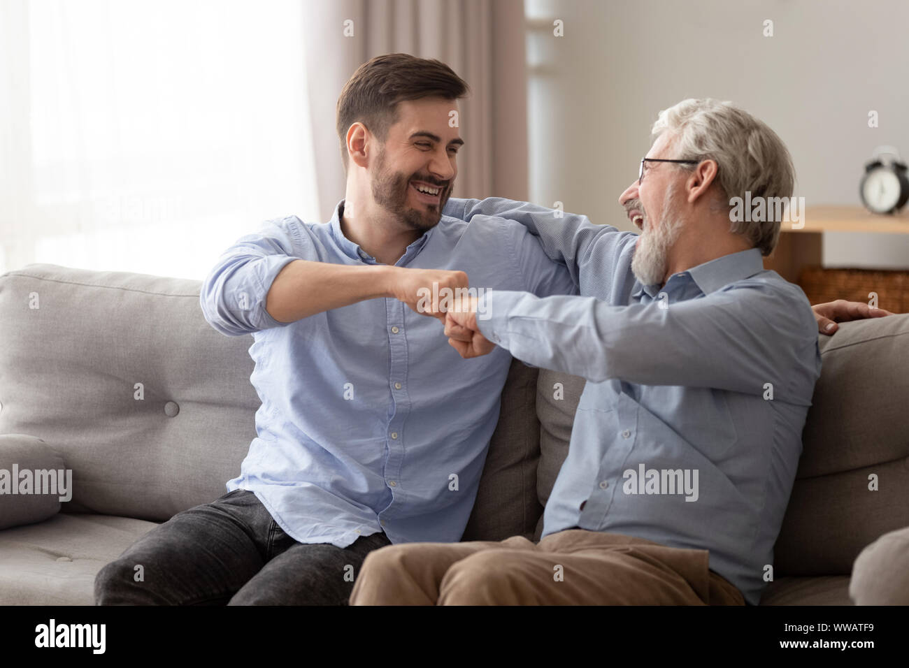 Felice senior Padre abbracciando giovane figlio dando fist bump Foto Stock