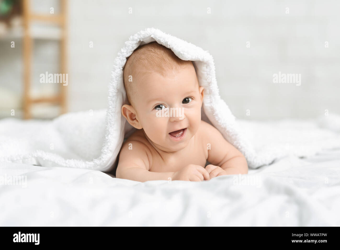 Felice piccolo bimbo gattona sul letto sotto coperta Foto Stock