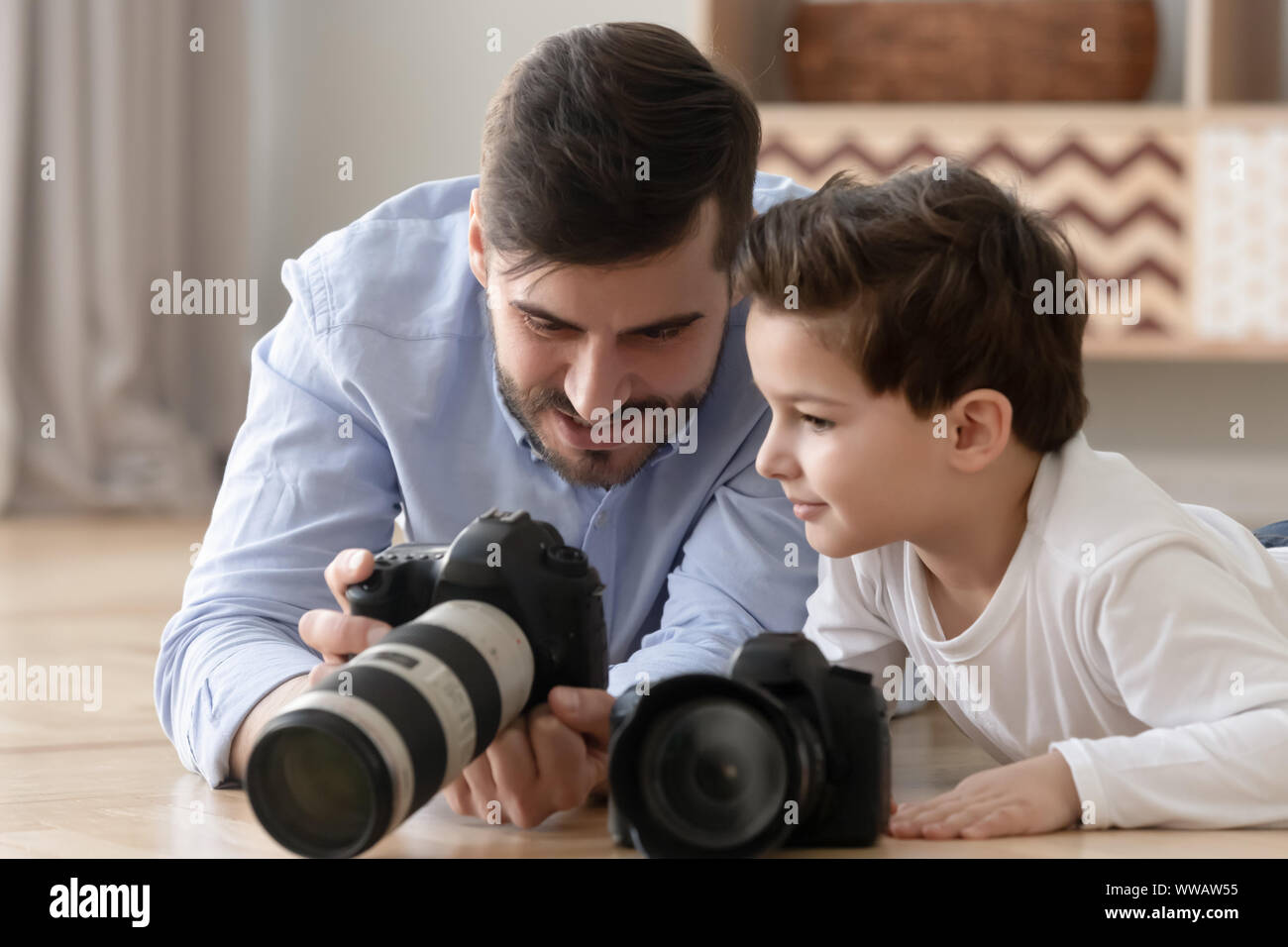 Felice papà e figlio di capretto riprodurre le fotocamere digitali a casa Foto Stock