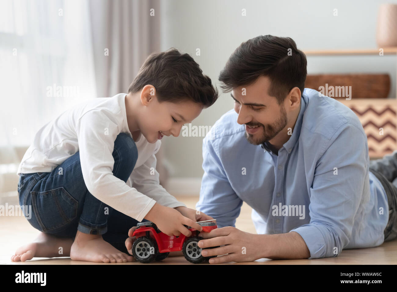 Felice papà e kid figlio giocare giocattolo auto a casa Foto Stock
