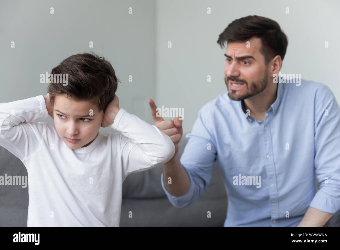 Padre arrabbiato grida di testardo pignolo piccolo figlio di orecchie di chiusura Foto Stock