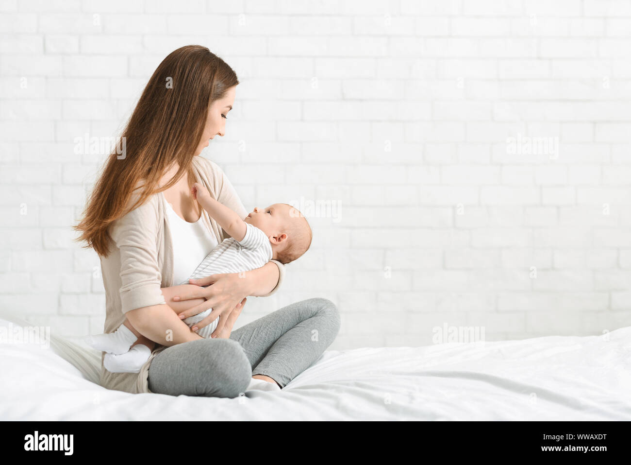 Giovane madre mentre tiene il suo figlio neonato, Lulling baby a letto Foto Stock