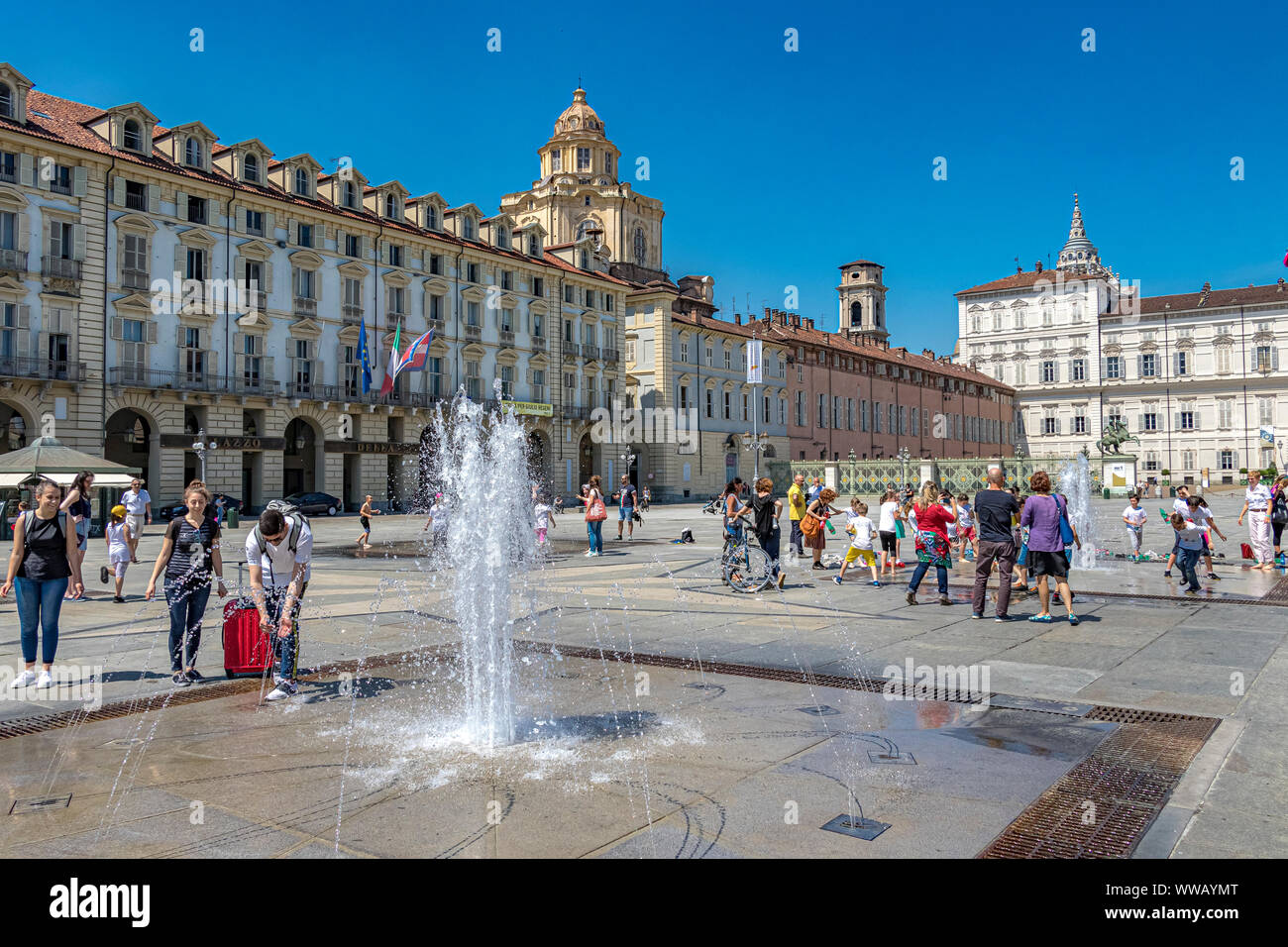 I bambini giocano nelle fontane di Piazza Castello, una piazza importante della città in una calda giornata estiva a Torino Foto Stock