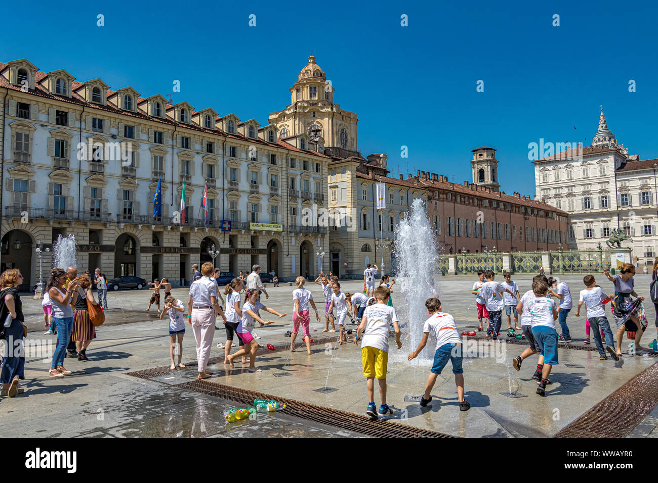 I bambini giocano nelle fontane di Piazza Castello, una piazza importante della città in una calda giornata estiva a Torino Foto Stock