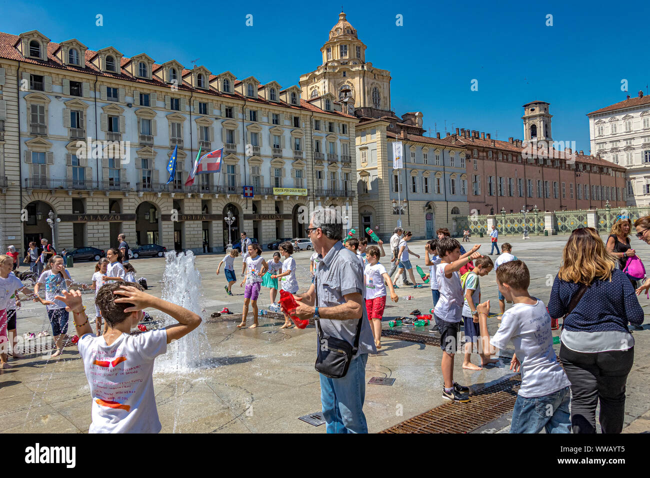 I bambini giocano nelle fontane di Piazza Castello, una piazza importante della città in una calda giornata estiva a Torino Foto Stock