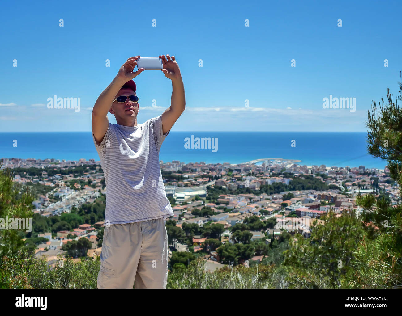 Giovane uomo prende un selfie sullo sfondo di un insediamento in riva al mare Foto Stock