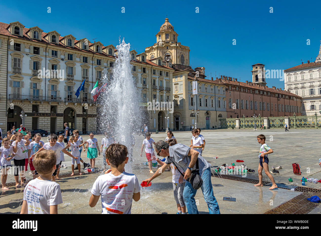 I bambini giocano nelle fontane di Piazza Castello, una piazza importante della città in una calda giornata estiva a Torino Foto Stock