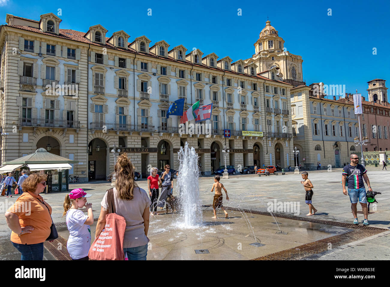 I bambini giocano nelle fontane di Piazza Castello, una piazza importante della città in una calda giornata estiva a Torino Foto Stock