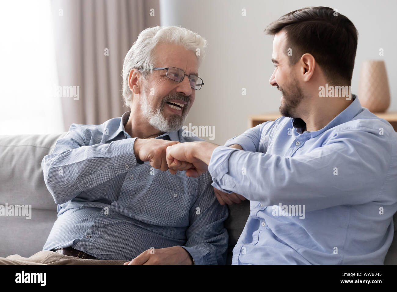Felice il vecchio padre e figlio giovane ridere dando fist bump Foto Stock