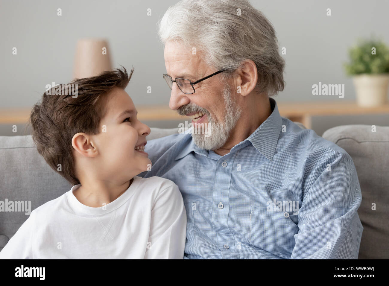 Sorridente senior nonno vecchio abbracciare ragazzino nipote a casa Foto Stock