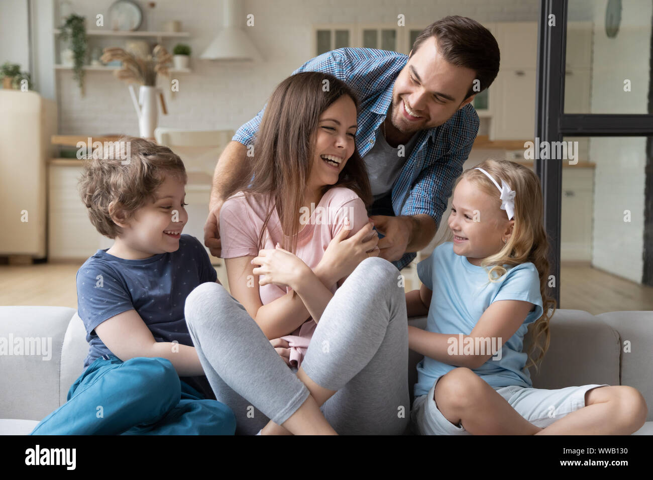 Giocoso felice giovane con bambini solletico ridere moglie madre. Foto Stock