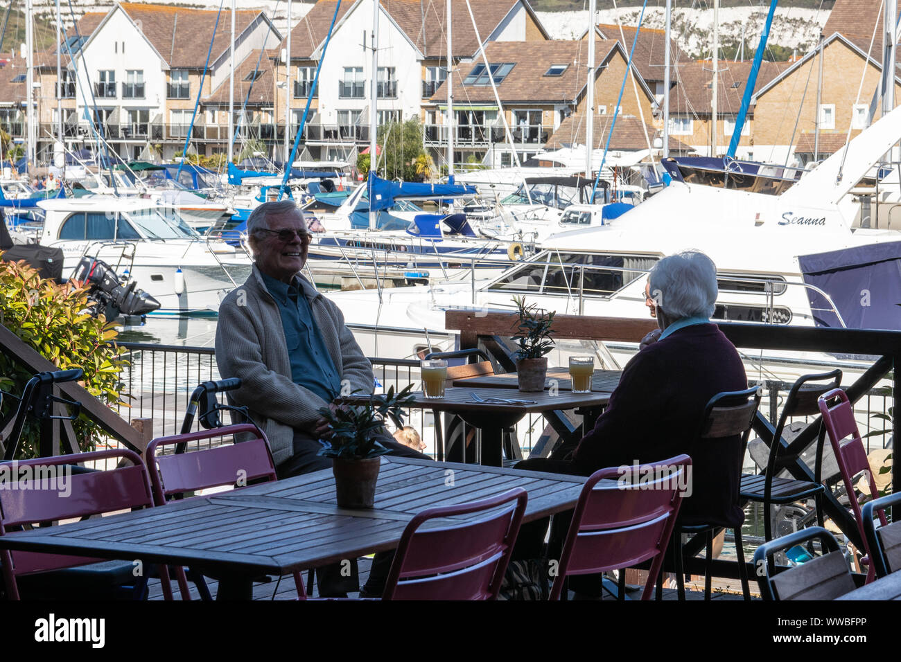 Una coppia di anziani gustando un drink al di fuori in un ristorante a uno yacht marina Foto Stock