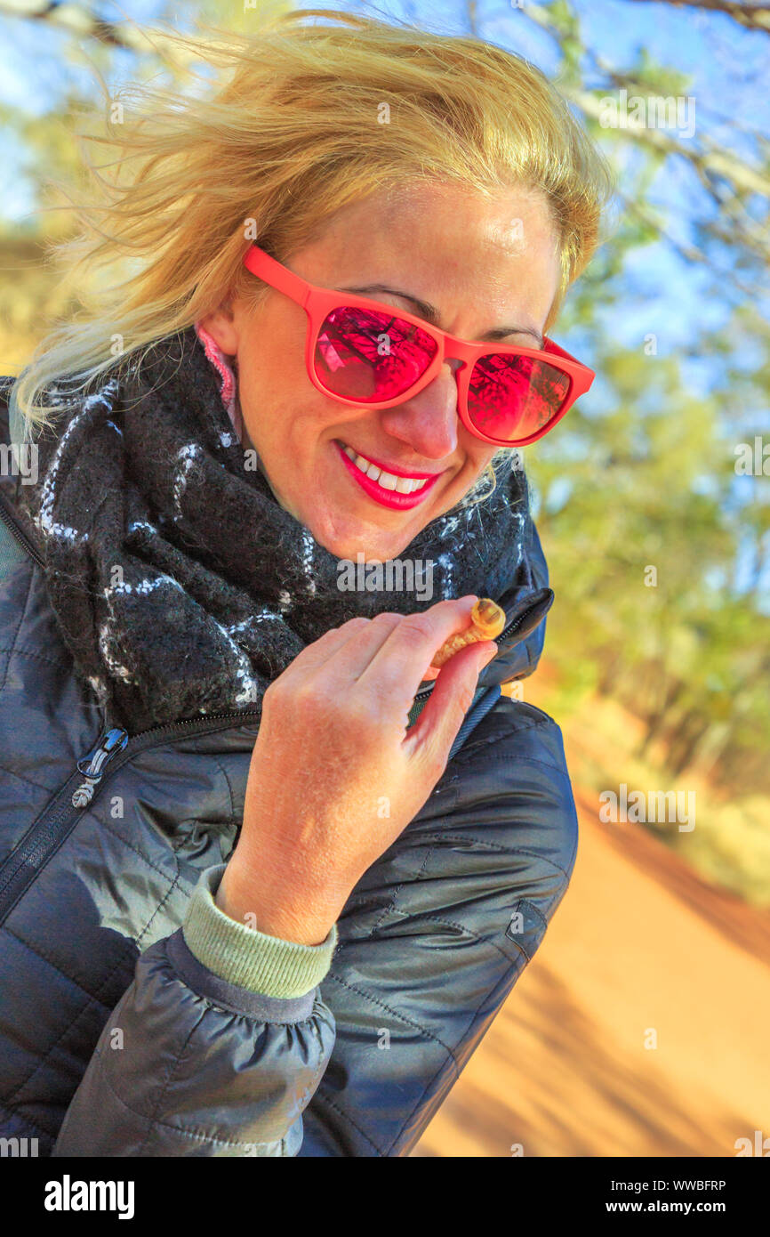 Donna turistico tenendo un Witchetty larve che si nutre delle radici della boccola witchetty comune nel Territorio del Nord, l'Australia. Il grub è stato il principale alimento Foto Stock